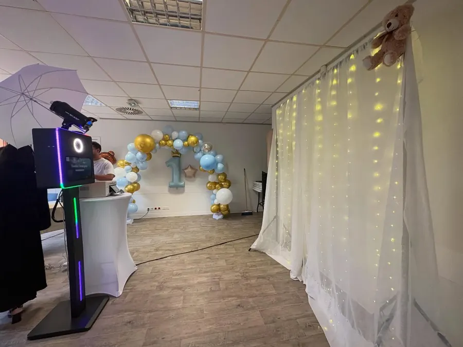 Photobooth classique face à une arche de ballons pour un premier anniversaire.